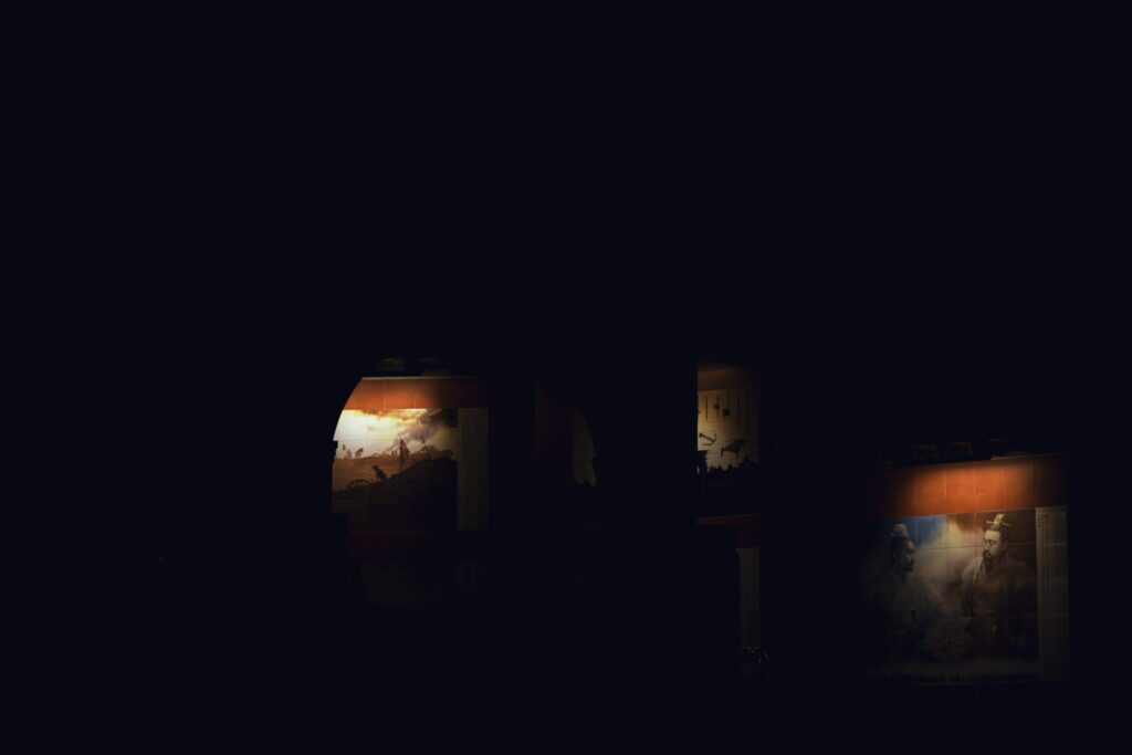 야간에 촬영한 인천 차이나타운의 삼국지 벽화. 어둠 속에서 조명이 비추는 벽화 일부가 드러나며, 역사적 인물들과 전통적인 장면들이 실루엣처럼 표현된다. 붉은 노을과 인물의 그림자가 어우러져 고대 중국의 서사적 분위기를 자아내며, 문화유산과 도시의 야경이 조화를 이루는 인상적인 장면이다.