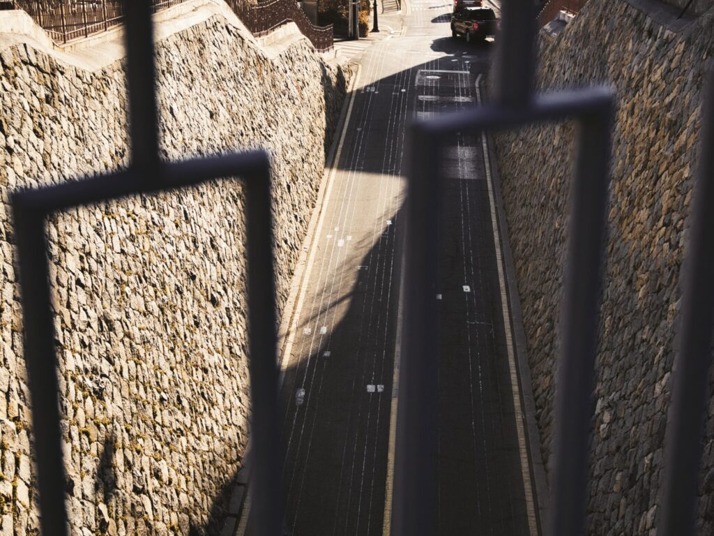 인천 중구 홍예문에서 내려다본 석축 사이의 좁은 골목길. 햇살이 비추는 도로 끝에 차량이 멀어져 가는 모습