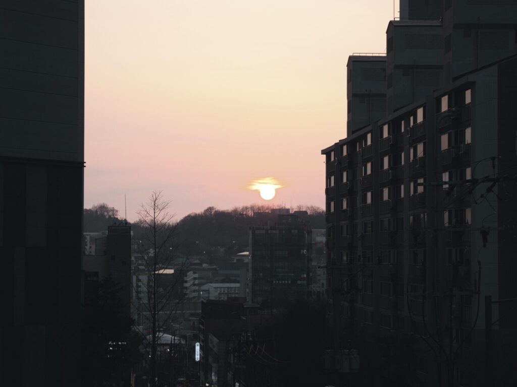 인천 동구 솔빛마을 아파트 사이로 보이는 일몰 풍경. 붉게 물든 하늘과 건물들이 어우러져 도시 속의 고요한 저녁 분위기를 자아냄.